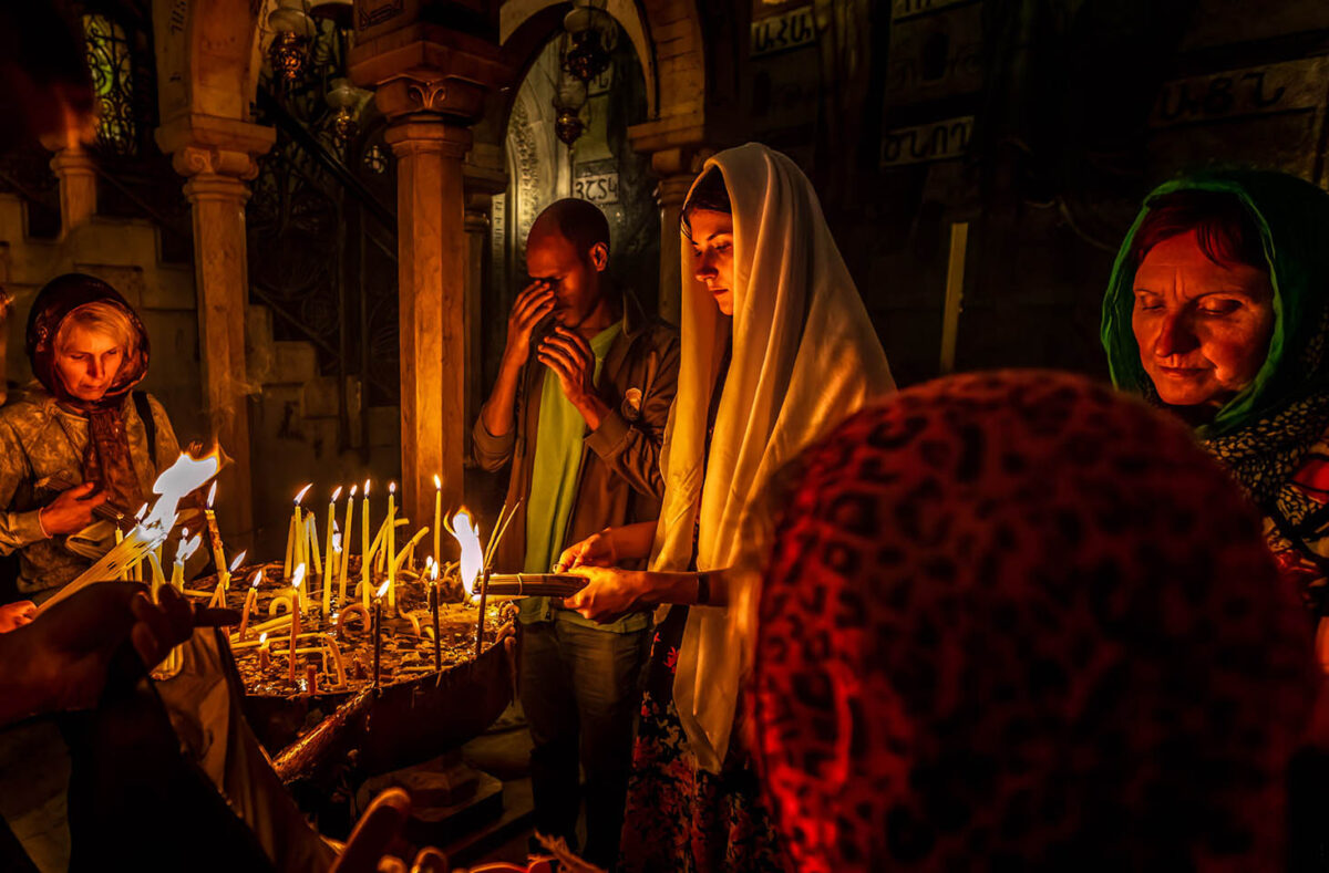 Worshippers light candles inside the Church of the Holy Sepulchre, their flames symbolizing faith, prayer, and Christ as the light of the world.